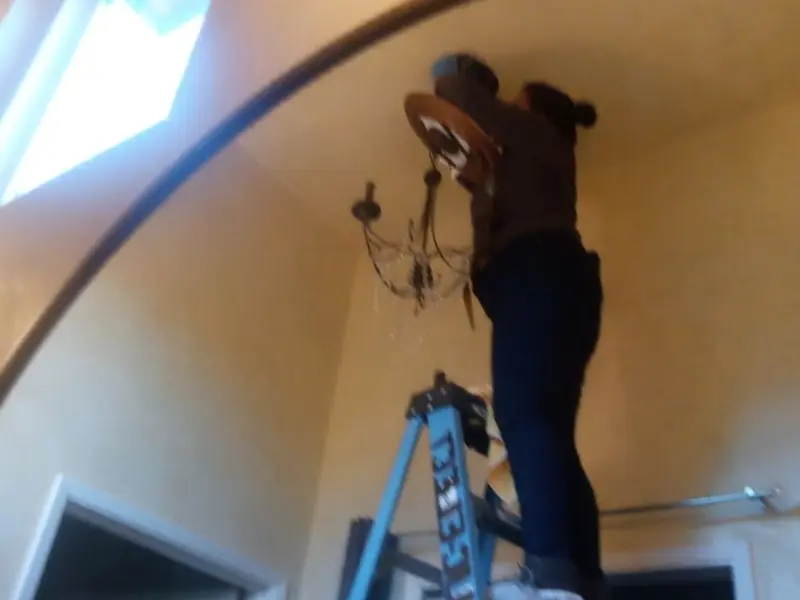 Electrician installing a chandelier in a Huron residence